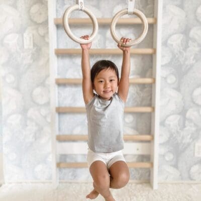Lapsi roikkuu ULPU MINI voimistelurenkaissa lastenhuoneessa, jossa on myös TAIMI MINI lasten puolapuut